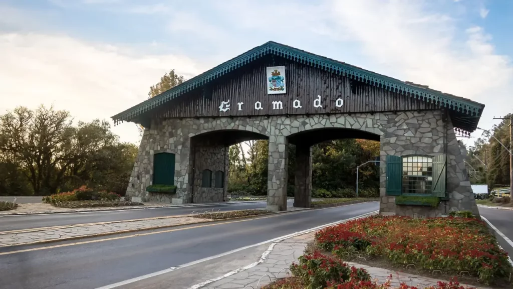 Pórtico de entrada de Gramado com jardins e flores, cenário para fotos Instagramáveis.